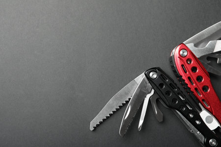 Compact portable multitool on gray background, top view. Space for text