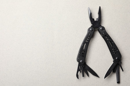 Compact portable black multitool on light gray background, top view. Space for textの写真素材