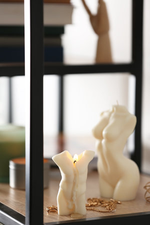 Beautiful body shaped candles and jewelry on shelf indoorsの写真素材