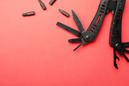 Compact portable black multitool and details on red background, flat lay. Space for textの写真素材