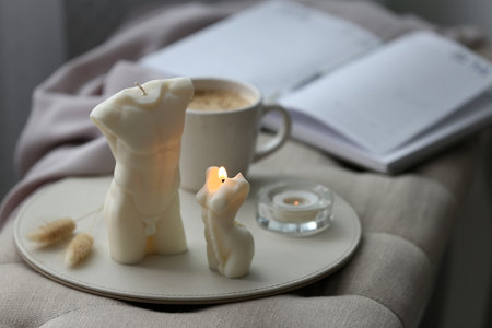 Beautiful body shaped candles and cup of hot drink on bench indoorsの写真素材