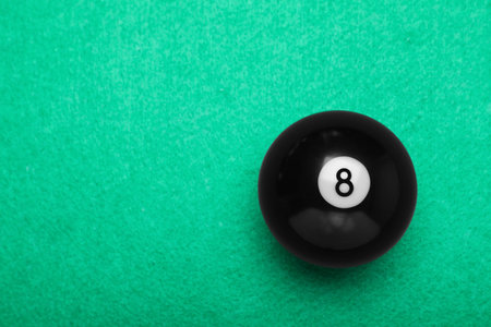 Billiard ball with number 8 on green table, top view. Space for textの写真素材