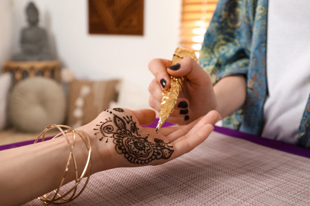 Professional mehndi master making henna tattoo indoors, closeupの写真素材