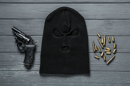 Balaclava, pistol and bullets on gray wooden table, flat layの写真素材