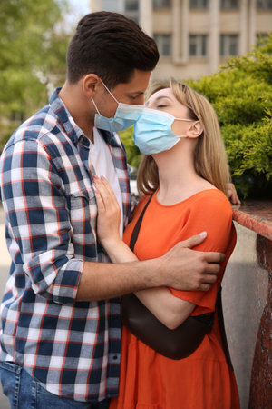 Couple in medical masks trying to kiss outdoorsの写真素材