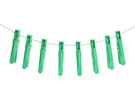 Green plastic clothespins hanging on rope against white backgroundの写真素材