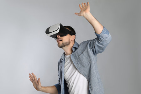 Man using virtual reality headset on gray background