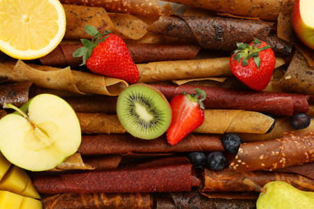 Delicious fruit leather rolls with ingredients as background, top viewの写真素材