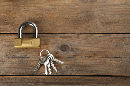 Modern padlock with keys on wooden table, flat lay. Space for textの写真素材