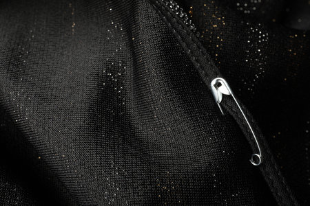 Metal safety pin on black fabric, closeupの写真素材