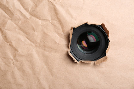 Hidden camera lens through hole in paper. Space for textの写真素材