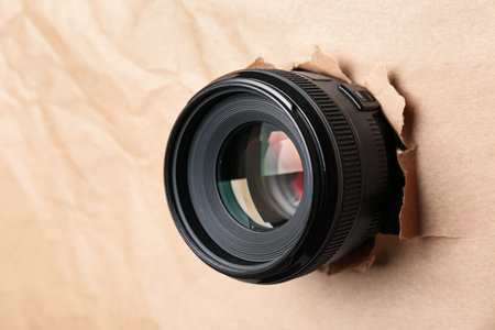 Hidden camera lens through hole in paper, closeupの写真素材