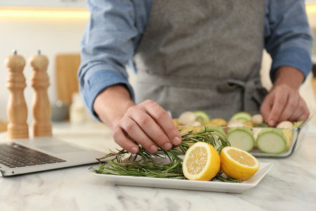 Man making dinner while watching online cooking course via laptop kitchen, closeupの写真素材