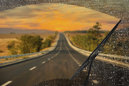 Car windshield wiper cleaning water drops from glass while drivingの写真素材
