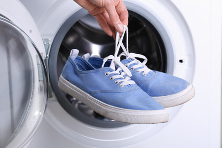 Woman putting pair of sport shoes into washing machine, closeupの写真素材