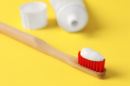 Wooden brush with toothpaste on yellow background, closeupの写真素材
