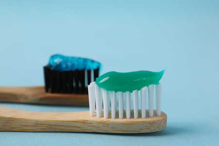 Wooden brushes with toothpaste on light blue background, closeupの写真素材