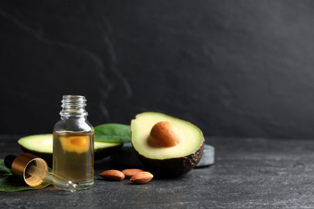 Essential oil, avocado and almonds on black table. Space for textの写真素材