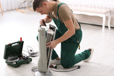 Professional technician repairing electric ultrared heater with screwdriver indoorsの写真素材