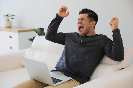Emotional man working with laptop at homeの写真素材