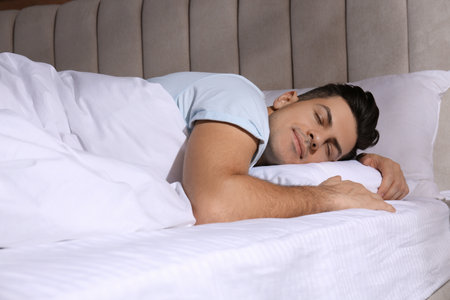 Man sleeping in comfortable bed with white linesの写真素材