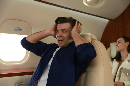 Scared young man suffering from aviophobia in airplane