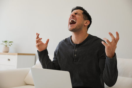 Emotional man working with laptop at homeの写真素材