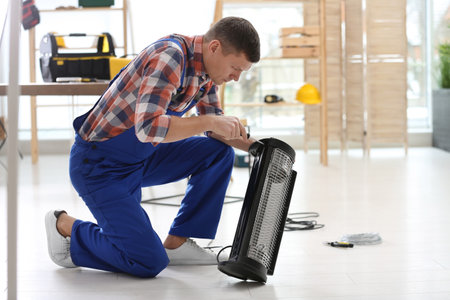 Professional technician repairing electric halogen heater with screwdriver indoorsの写真素材