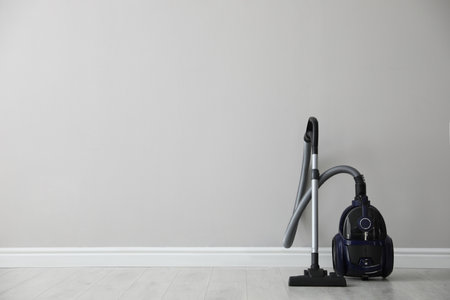 Modern vacuum cleaner near white wall indoors, space for textの写真素材