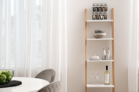 Stylish ladder shelf with kitchenware in dining roomの写真素材