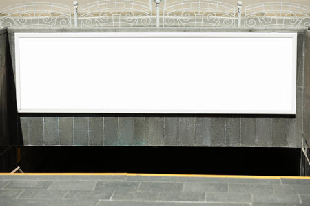 Blank advertising board hanging on wall near underground passage