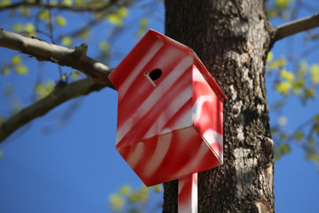 Red and white bird house on tree outdoorsの写真素材