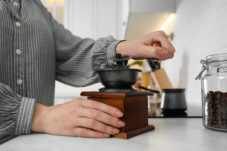 Woman using vintage coffee grinder at countertop indoors, closeupの写真素材