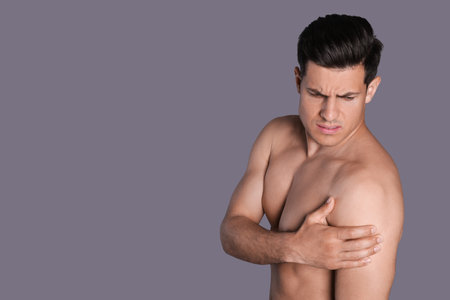 Man suffering from shoulder pain on gray background. Space for textの写真素材