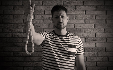Depressed man with rope noose near brick wall. Suicide conceptの写真素材