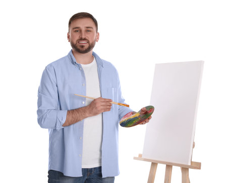 Man with painting tools near easel on white background. young artistの写真素材