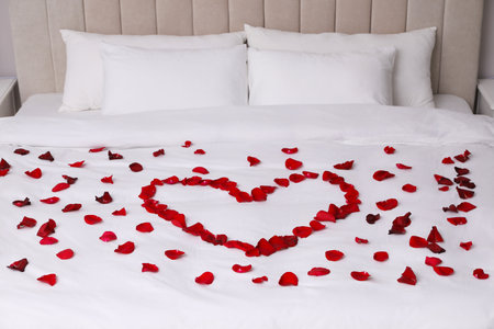 Beautiful heart of red rose petals on bedの写真素材