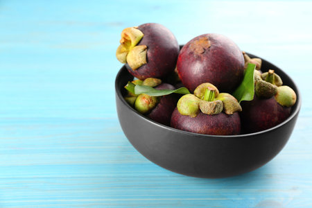 Fresh ripe mangosteen fruits on light blue wooden table. Space for textの写真素材