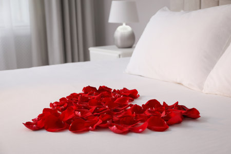 Beautiful heart of red rose petals on bed in roomの写真素材