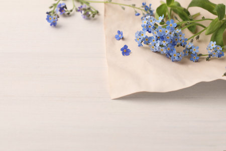 Beautiful Forget-me-not flowers and parchment on white wooden table. Space for textの写真素材