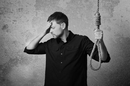 Depressed man with rope noose near wall. Suicide conceptの写真素材