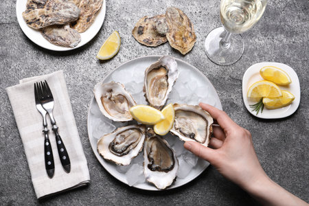 Woman eating tasty fresh oysters at gray table, top viewの写真素材