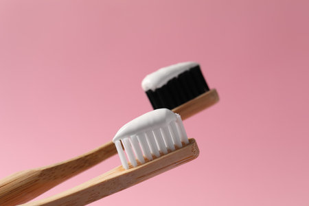Wooden brushes with toothpaste on pink background, closeupの写真素材