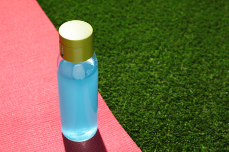 Bottle of light blue drink and mat on green grass, space for textの写真素材