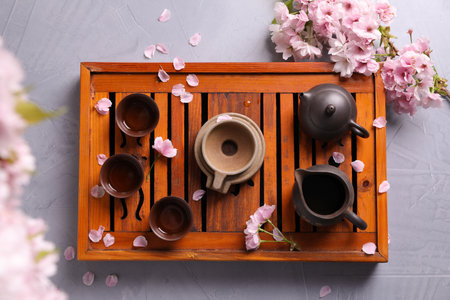 Beautiful set for traditional tea ceremony and sakura flowers on light gray table, flat layの写真素材