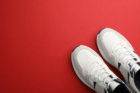 Pair of stylish sports shoes on red background, flat lay. Space for textの写真素材