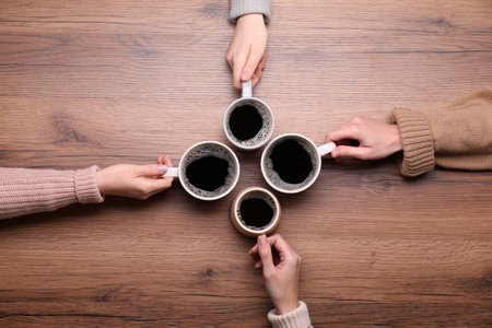 Women with cups of coffee at wooden table, top viewの写真素材