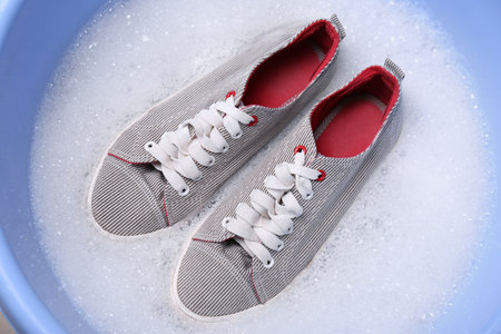 Washing pair of sport shoes in plastic basinの写真素材