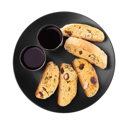 Black plate with tasty cantucci and glasses of liqueur on white background, top view. Traditional Italian almond biscuitsの写真素材