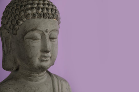 Beautiful stone Buddha sculpture on violet background, closeup. Space for textの写真素材